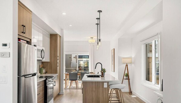 Una cocina moderna con refrigerador de acero inoxidable, armarios de madera y una isla central con taburetes de bar.