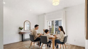 Un coin repas comprenant une table, des chaises, une plante et un miroir au mur.