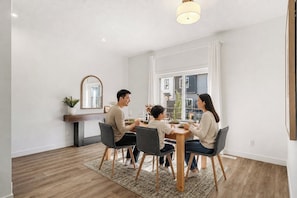A dining area with a table, chairs, a plant, and a mirror on the wall.