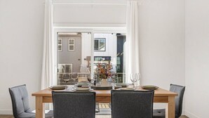 Un coin repas avec une table en bois dressée pour quatre personnes, des chaises grises à revêtement rembourré et un vase rempli de fleurs.
