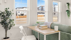 Una habitación con un sofá verde, una mesa de madera, una silla blanca y una planta en maceta.