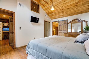 A bedroom with a large bed, wooden ceiling, a television, and a dresser with a mirror. - Pet-Friendly Ski, Swim & Relax Poconos Getaway (Pocono Pines)