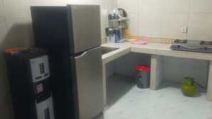 A compact kitchen with a refrigerator, a water dispenser, a sink, and a gas stove. - Pradnya Homestay - 1Bedroom Near Uluwatu (Ungasan)