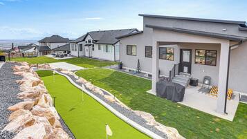 A modern residential area with houses, a well-maintained lawn, and a golf course.