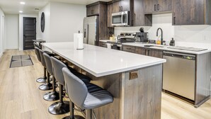 Una cocina moderna con armarios de madera oscura, electrodomésticos de acero inoxidable y una encimera blanca.