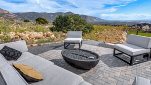 Un patio con mobiliario exterior, una chimenea y una vista panorámica de la montaña.