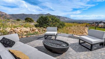 A patio with outdoor furniture, a fire pit, and a scenic mountain view.