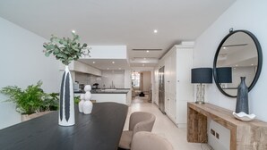 Een moderne keuken met witte kastjes, een donker houten eettafel en een grote spiegel.