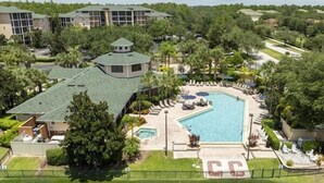 A resort with a swimming pool, multiple buildings, and lush greenery.
