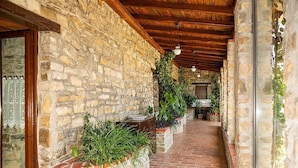 A stone-walled corridor with a tiled floor, wooden beams, and potted plants.