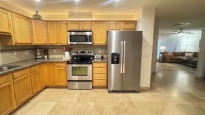 A modern kitchen with wooden cabinets, stainless steel appliances, and a tiled floor. - Old Town Scottsdale / 4 Bedroom House (Scottsdale)