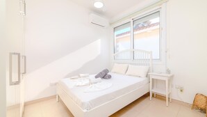 Une chambre à coucher comprenant un lit, une table de chevet, une fenêtre et un appareil de climatisation.