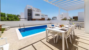 A rooftop pool area with a table and chairs, a pool ladder, and a pergola. - Elite Blu Heights Villa (Ayia Napa)