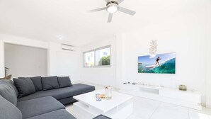 A modern living room with a grey sectional sofa, a white coffee table, and a flat-screen TV mounted on the wall. - Elite Blu Heights Villa (Ayia Napa)