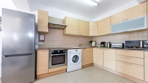 A modern kitchen with stainless steel appliances, wooden cabinets, and a built-in washing machine. - Nissi Apartment #102 (Ayia Napa)