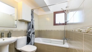 A bathroom with a toilet, sink, bathtub, and shower. - Nissi Apartment #102 (Ayia Napa)