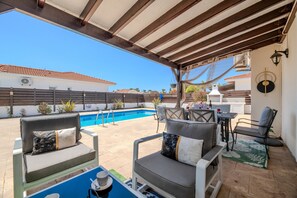 Eine Terrasse im Freien mit Pool, Sitzgelegenheiten und einem überdachten Bereich.