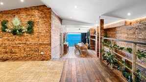Un interior moderno con paredes de madera, una zona de comedor con vistas al mar y una pared verde.