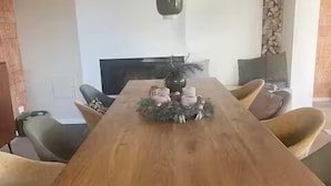 A dining room with a long wooden table, four chairs, a television, and a decorative centerpiece.