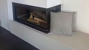 A modern fireplace with a built-in bench and a cushion.