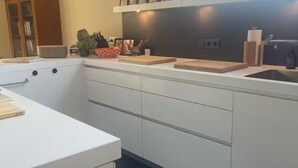 A modern kitchen with white cabinetry, a black tiled backsplash, and a window providing natural light.