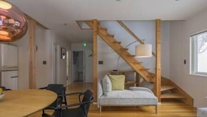 Un interior moderno con una escalera de madera, un comedor con mesa redonda y un sofá.