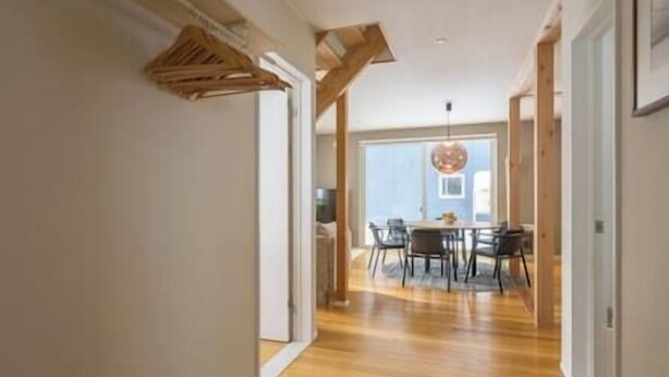 Un pasillo con piso de madera y un comedor con mesa y sillas.