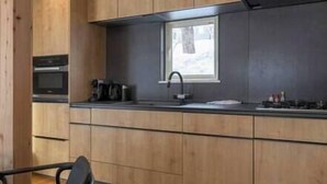 Una cocina moderna con armarios de madera, horno integrado, pileta y ventana.