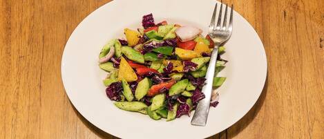 Un plato blanco con una ensalada de verduras coloridas sobre una mesa de madera.