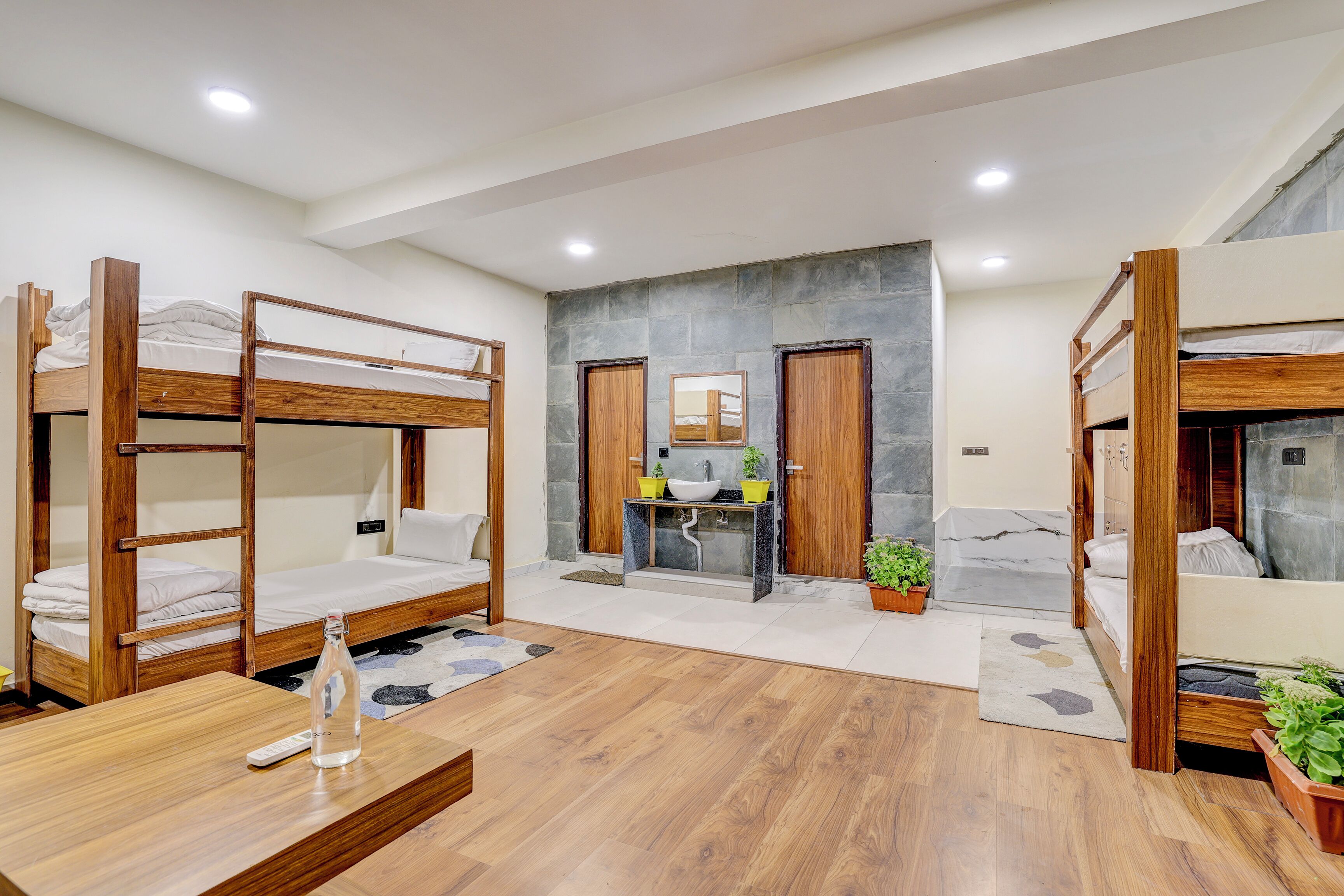 A bunk bed room with a wooden floor, a small sink, and a mirror.