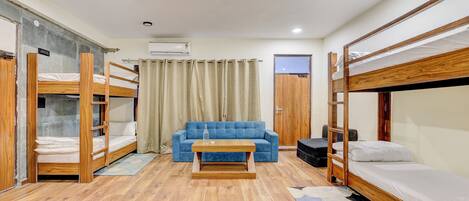 A room with bunk beds, a sofa, a coffee table, and an air conditioning unit.