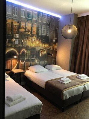 Habitación de hotel con dos camas, un mural de paisaje urbano, una lámpara colgante y una cortina marrón.