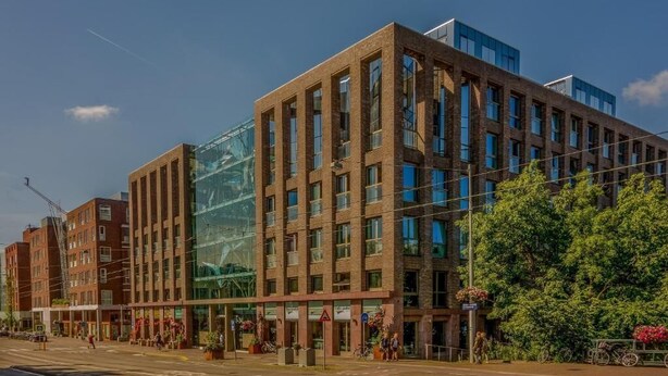 A modern building with a glass facade, multiple floors, and a mix of brick and glass construction.