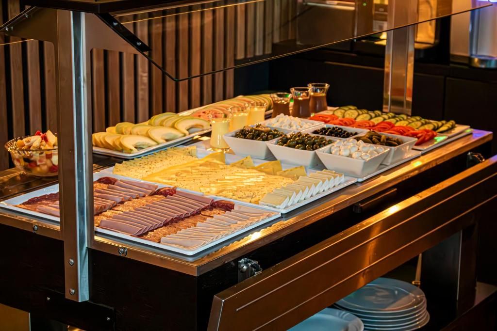 Un bufé con una variedad de alimentos, incluyendo carnes, quesos, frutas y verduras.