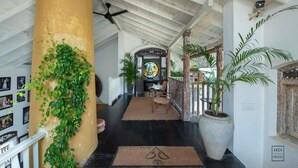 A spacious hallway with a high ceiling, a large column with greenery, a large potted plant, and a decorative wall with a circular design. - Prince of Galle (Galle)
