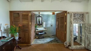 A hallway with wooden doors, a stone floor, a sink, and a mirror. - Prince of Galle (Galle)