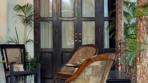 A traditional room with a dark wooden door, two wicker chairs, and a small table. - Prince of Galle (Galle)