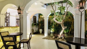 A spacious indoor area with a round table and chairs, surrounded by white arches and potted plants. - Prince of Galle (Galle)