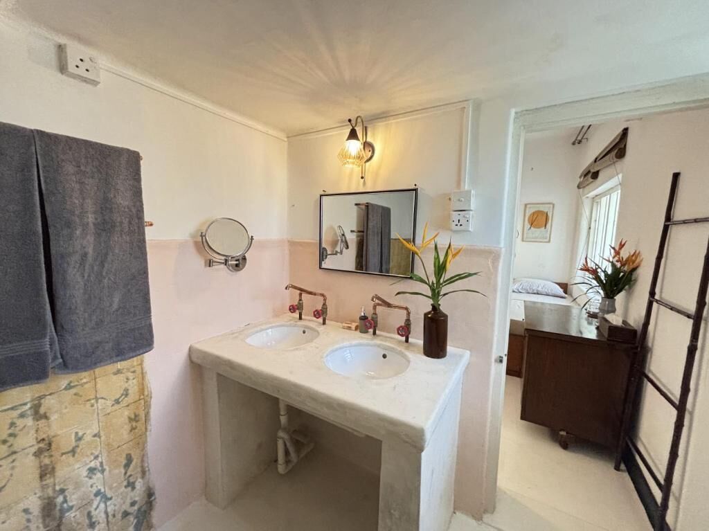 Une salle de bain avec deux lavabos, un miroir et un espace douche.