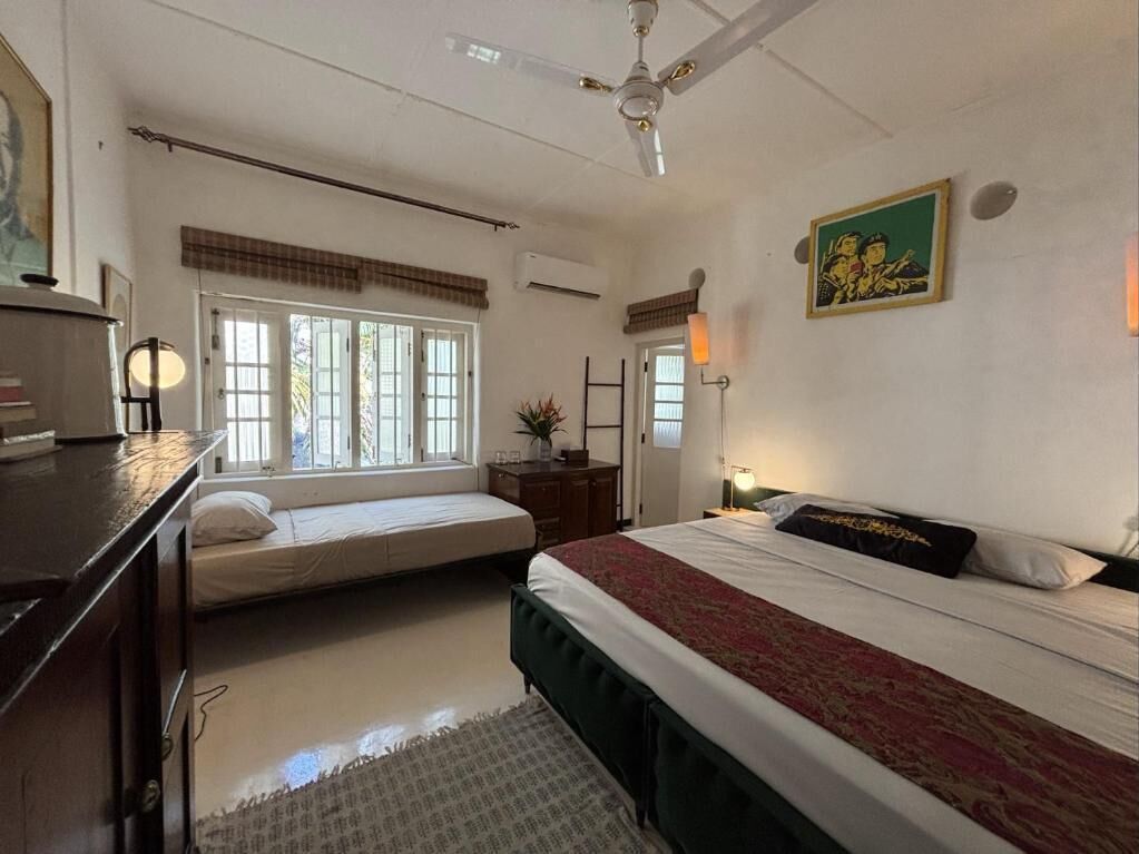 A bedroom with a bed, bedside table, lamp, window, and ceiling fan.