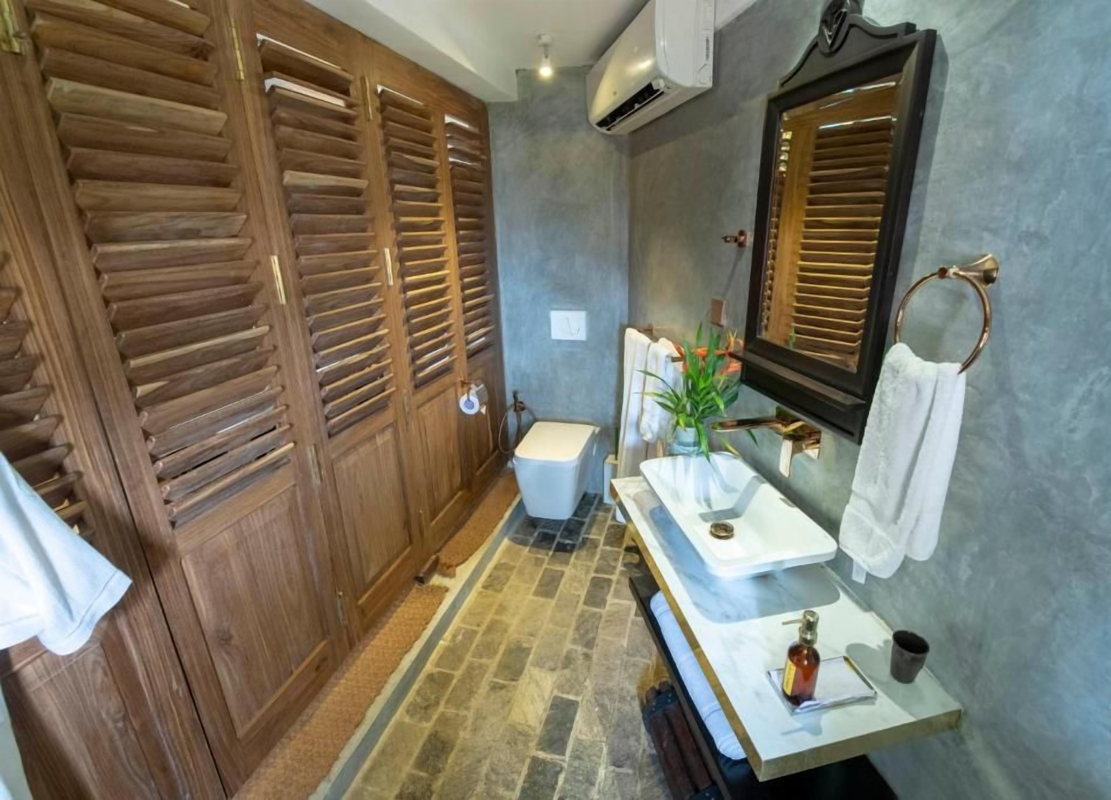 Une salle de bain avec un meuble-lavabo en bois, un lavabo blanc, un miroir et un porte-serviettes.
