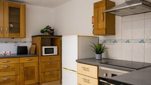 A kitchen with wooden cabinets, a microwave, a refrigerator, and a stove.