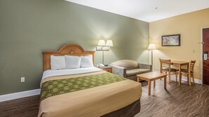 Une chambre d’hôtel avec un lit, un bureau, une chaise, une lampe et un tableau au mur.
