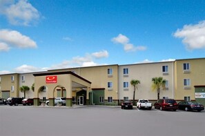 Un hôtel doté d’une entrée principale, de nombreux espaces de stationnement et offrant une vue sur un ciel dégagé.