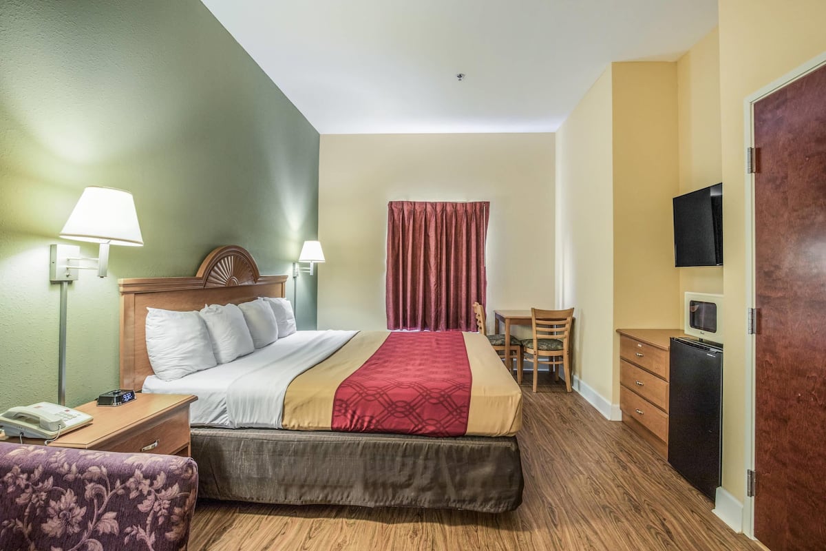Ein Hotelzimmer mit Bett, Nachttischen, Schreibtisch, Stuhl, Fernseher und Kleiderschrank.
