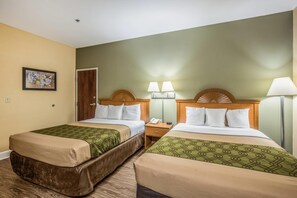 Une chambre d’hôtel avec deux lits, une tête de lit en bois, des lampes de chevet, une table de chevet et un tableau encadré au mur.
