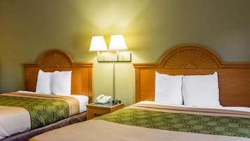 A hotel room with two beds, each with a patterned bedspread, a nightstand with a lamp, and a wall-mounted light fixture.