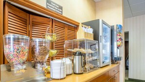Ein Frühstücksbuffet mit Müsli, Gebäck und einer Kaffeemaschine.
