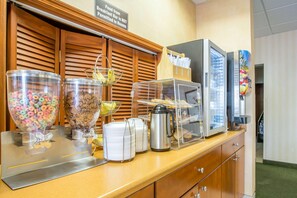 Un buffet pour le petit-déjeuner proposant des céréales, des viennoiseries et une machine à café.