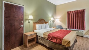 Une chambre d’hôtel avec un lit en bois, des tables de chevet, des lampes, une fenêtre avec des rideaux et une porte.
